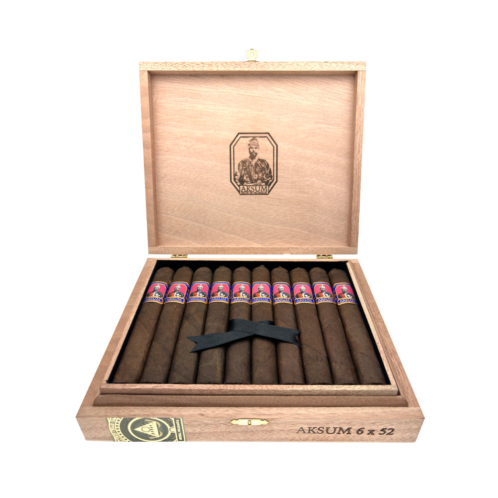 Open wooden cigar box with Aksum branding containing neatly arranged cigars with colorful bands and a black ribbon.