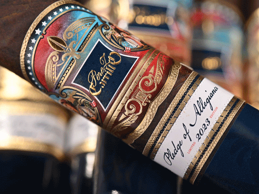 Close-up of a decorative cigar band featuring intricate designs and text reading "Perez Carrillo Pledge of Allegiance Limited 2023 Edition" on a dark background.